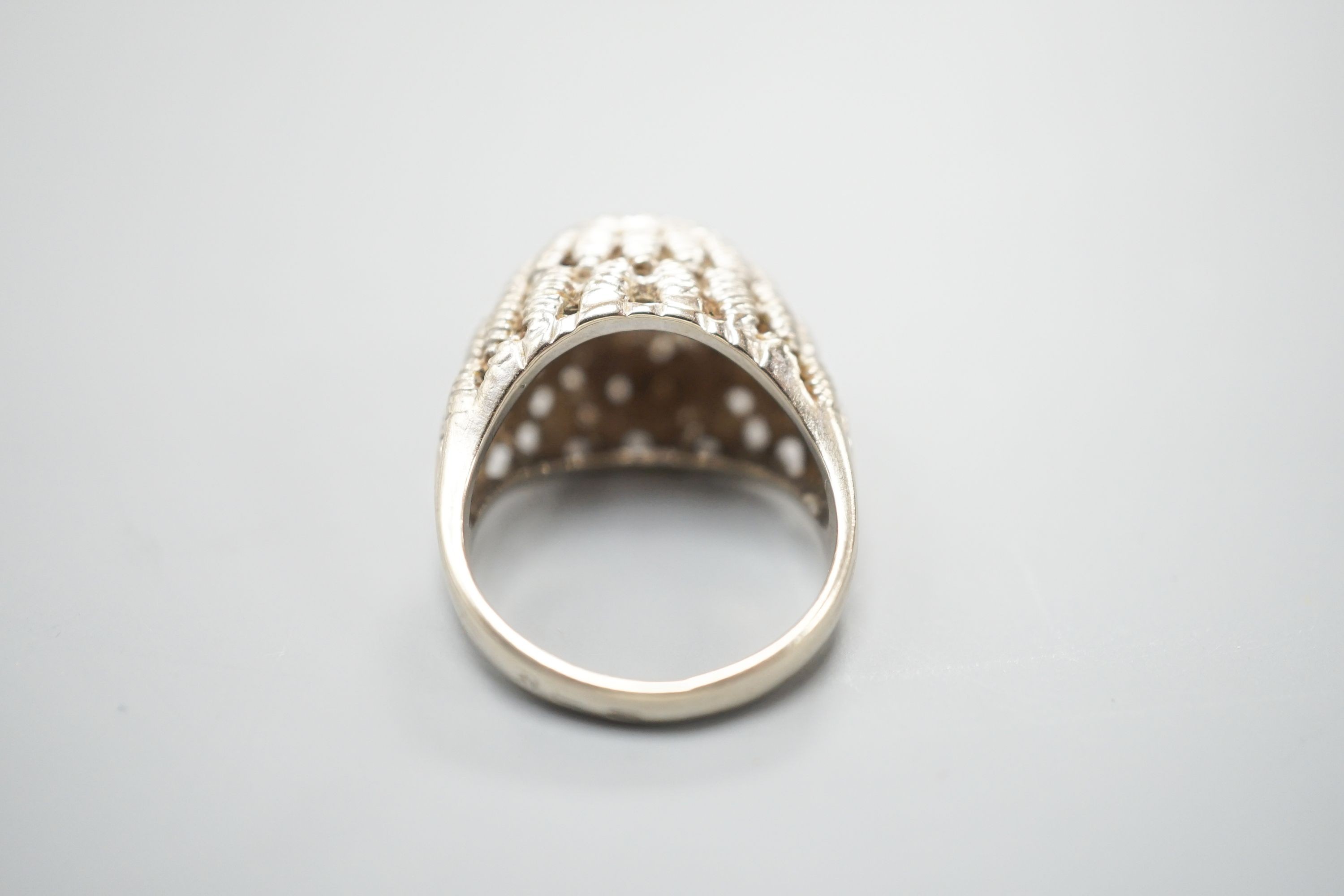 A continental textured white metal and diamond cluster set domed top dress ring, size K/L, gross weight 5.5 grams.
